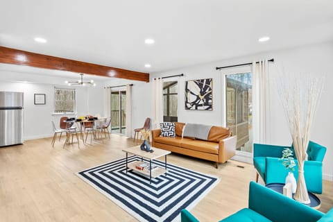This airy layout seamlessly connects the living and dining areas, with contemporary furnishings, warm wood flooring, and a bright, inviting atmosphere.
