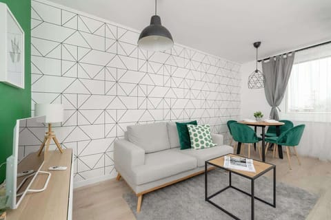 A stylish living room with a white geometric-patterned wall, a grey sofa, and a small table.