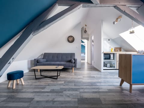 "This open kitchen is bathed in natural light thanks to a well-placed window. The white and blue walls create a bright atmosphere. The kitchen is functionally equipped, with a comfortable seating area nearby. The dining room is also integrated into this room, promoting conviviality during meals. This space combines functionality, brightness and style."