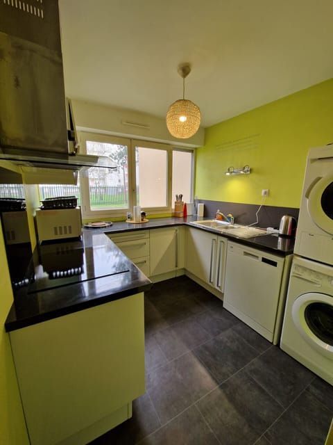 "Discover the chartreuse-yellow kitchen of the Le Square property in Le Mans through this photo. The kitchen is fully equipped and furnished, including a washing machine, tumble dryer, dishwasher and microwave. You can also see the four windows at the back of the room. Enjoy a bright and functional space to prepare delicious meals during your stay."