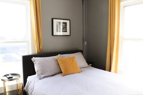 Lounge in plush bedding framed by bright corner windows.