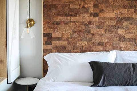 Feel boutique comfort with statement wall and glowing bedside pendant.