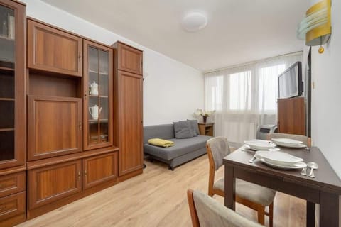 A cozy living room with traditional wooden cabinets, a dining table with chairs, and a comfortable gray sofa, creating a warm and inviting atmosphere.


