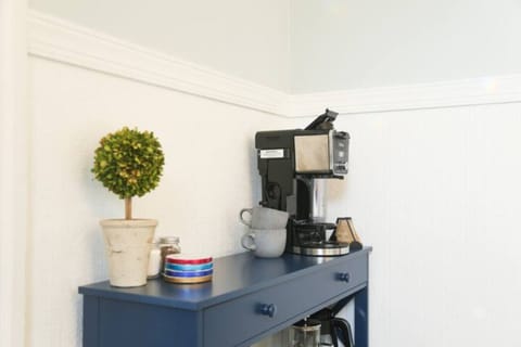 A convenient coffee station with a modern coffee maker, cups, and a decorative plant, perfect for a quick caffeine fix.