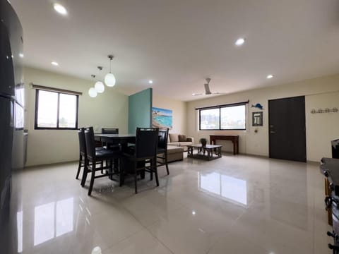 Open dining and living area with dark wood furniture, cream sofa, and large windows flooding light.