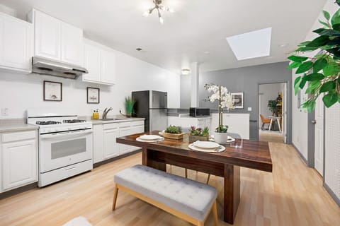 Warm kitchen lit by the sun, with a simple wooden table and bench.