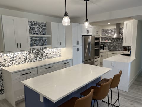 Open kitchen with huge island and 3 barstools.