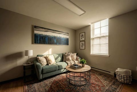 Sitting area with sofa, coffee table, large window, and wall art.