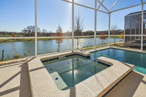 Relax in your private hot tub, framed by a screened enclosure that offers breathtaking views of the tranquil water. The sleek stone surfaces and gentle ripples of the pool create an inviting atmosphere for unwinding under the sun.