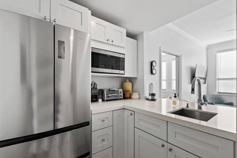 Kitchenette with a Toaster oven, microwave, fridge, Keurig coffee maker, glasses, plates, and cutlery.

