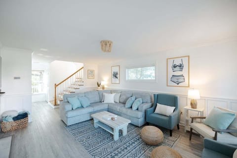 Bright and inviting living room featuring an electric fireplace, plush seating, blackout curtains, and coastal décor.