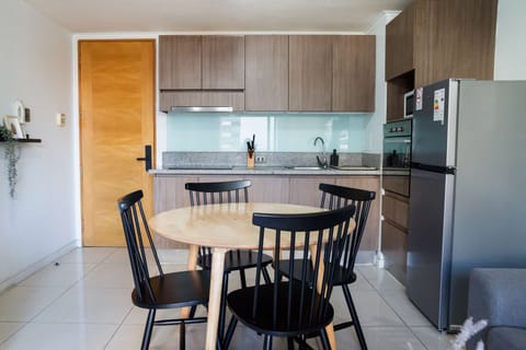 Modern kitchen with sleek design and dining area, perfect for cozy meals in your Chilean apartment getaway.