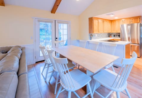 A great space for relaxation and meals, complete with a light wooden dining table, pastel-colored chairs, and a plush couch in close proximity, ideal for socializing.