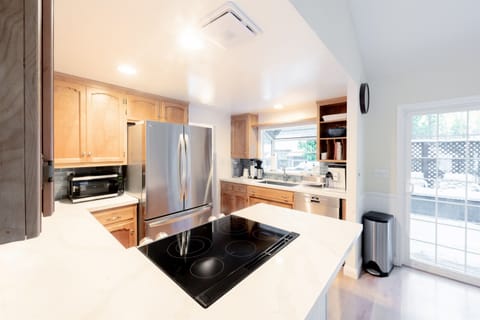 Clean and modern look with white countertops, stainless steel appliances, and wooden cabinetry.