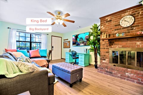 The living room's colorful statement boasts a 65" SMART TV and work desk. 