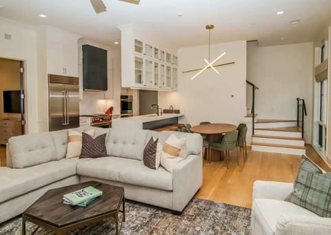 A cozy, designer-curated seating area featuring a large flat-screen TV and elegant light fixtures.