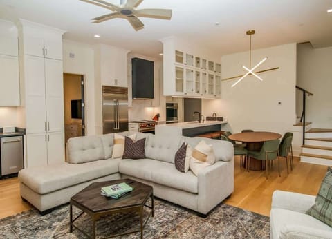 Bright, open-concept living area with plush sectional seating, warm hardwood floors, and seamless flow into the dining space.