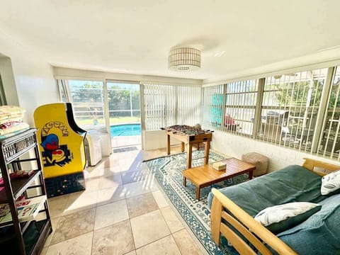 Sun room filled with games including a pac man arcade game and foosball table
