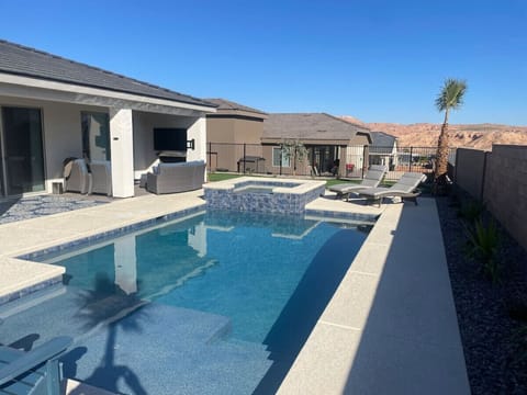 Outdoor bliss - pool, hot tub, lounger chairs, sitting area with fire place, and smart TV.