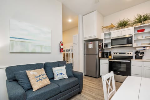 Relax in this bright, coastal-themed space where your fully equipped kitchen meets cozy living area—perfect for cooking and unwinding after beach adventures.