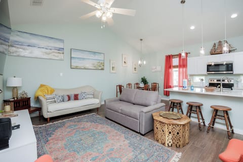 Relax in your bright open living space with coastal artwork, comfy seating, and a fully equipped kitchen perfect for vacation meals.