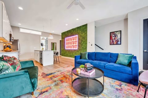 The neon 'HOWDY HOWDY HOWDY' sign and moss accent wall set the mood for group photos every night, while ping pong rematches spill into the open living room