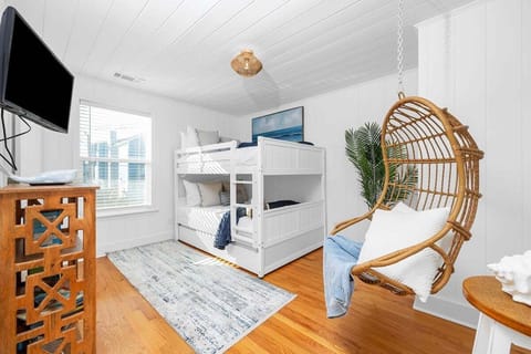 In Bedroom 1, the charm of a bunk bed pairs perfectly with the unique allure of a wooden hanging chair—a delightful space for both slumber and swing