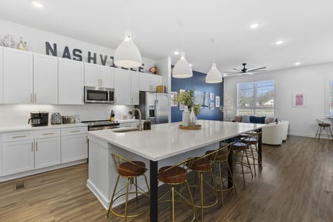 Huge kitchen on the main floor of the house with  a massive island, wine cooler, tons of seating, and all the appliances / supplies you'd need to cook a meal.