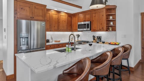 Your gourmet kitchen awaits with rich wood cabinetry, marble island, and premium appliances perfect for creating memorable meals together.