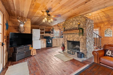 Cabin living room with a stone fireplace, a cozy and inviting gathering space.
