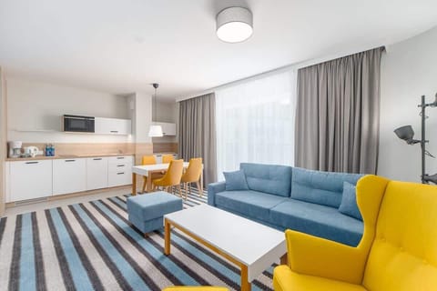 A wide-angle view of the living and dining space, featuring a striped rug, a yellow armchair, and a modern open layout.
