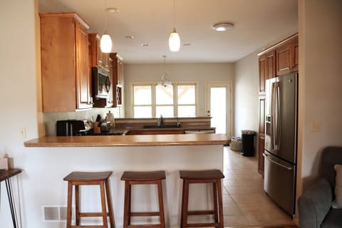 Kitchen area. Seating at the bar and there is a dining room table by the windows.