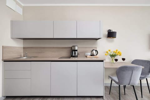 Kitchenette with minimalist cabinets, coffee maker, and yellow floral decoration.