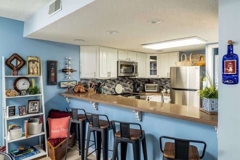 Bar looking into kitchen- 4 stools increasing dining seating to 10. Shelves containing children’s books & games