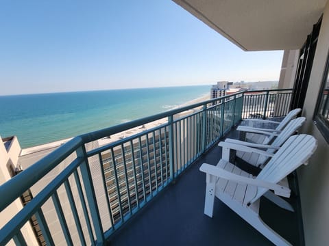 Three seated adirondack chairs on the breezy ocean side.