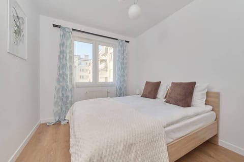 Bedroom with double bed, beige bedding, and large window for natural light.
