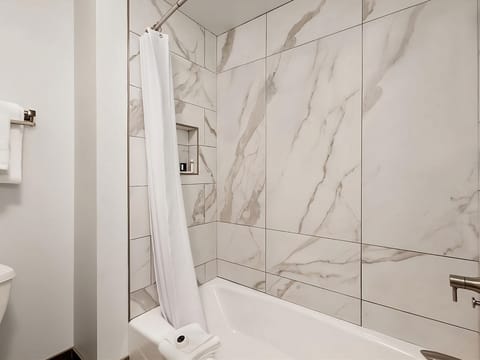 Soak and reset in a sleek marble-tiled tub shower.