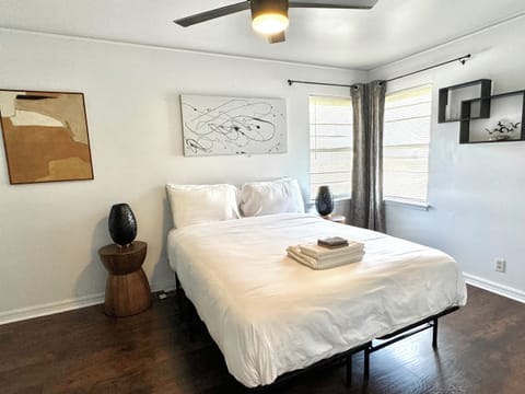 Bedroom — queen bed with accent wall and corner windows.