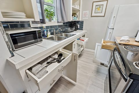 Fully stocked and thoughtfully organized—this galley kitchen features a double sink, microwave, dishware, utensils, and all the basics for cooking or reheating meals with ease.