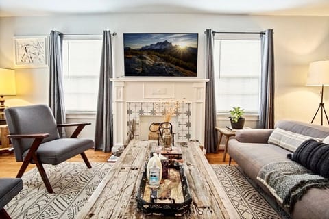 A cozy living room bathed in sunlight streaming through a large window with comfy sofa & TV