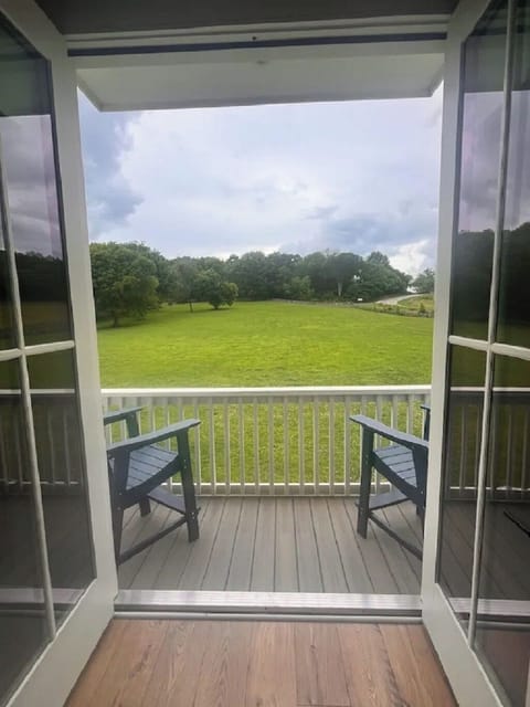 Balcony off bedroom with two chairs and tables on each side of the chairs.