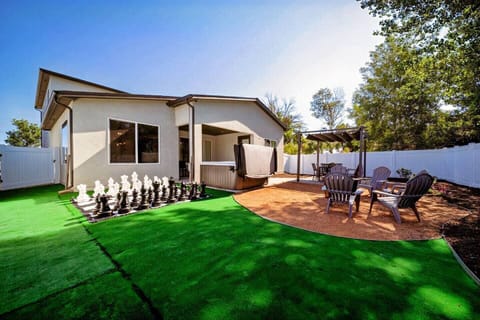 A vibrant backyard space with a giant chess set for strategic minds, and a cozy pergola for those seeking relaxation in the shade