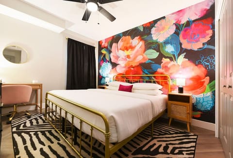 Vibrant and cozy bedroom featuring a bold floral accent wall and a comfortable bed.