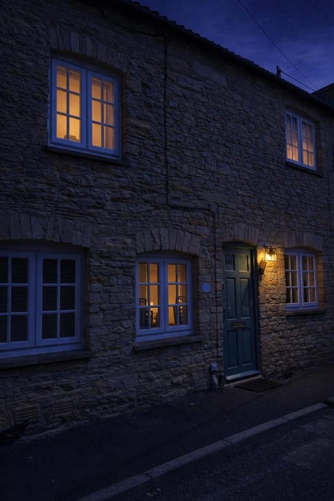 The front of Alexis Cottage at sunset, with golden light catching the stonework and setting the tone for a calm and comfortable stay in the heart of the Cotswolds.