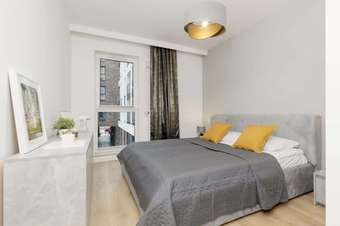 Stylish bedroom with a plush gray bed, golden accents, and a modern balcony view.
