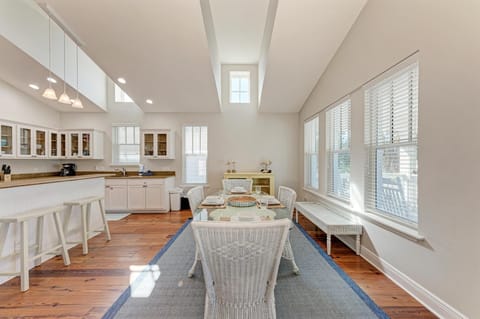 Gather around your glass dining table in this bright, open kitchen-dining space with white cabinetry and warm wood floors.
