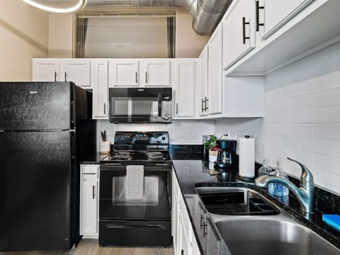 Fully equipped kitchen with black appliances and sleek granite countertops - White cabinets and subway tile backsplash enhance the modern design - Cook your favorite meals with ease using the stove, microwave, and coffee maker
