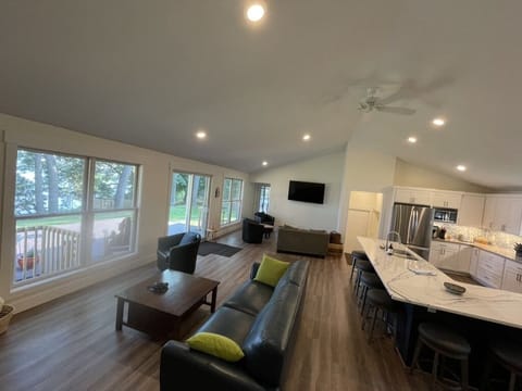 Wall of windows and sliding door opening onto deck overlooking lake.