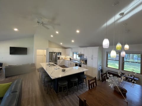 Kitchen with cathedral ceiling, showing large wall TV in cozy sitting area. 