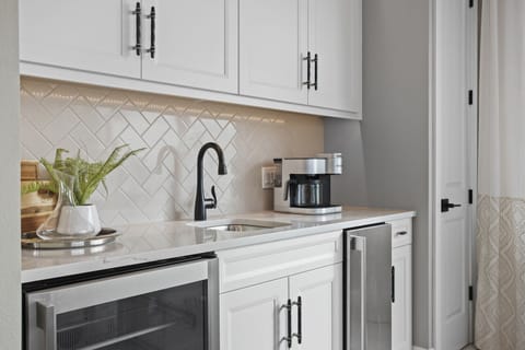 Wet bar with ice maker, beverage fridge, sink, and coffee station. 